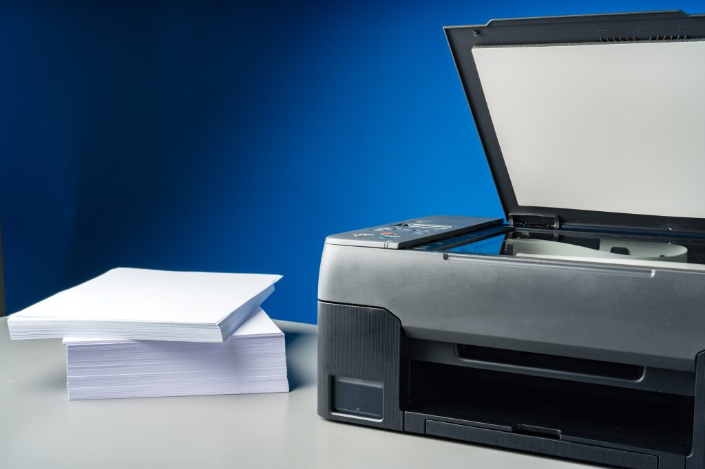 Laser printer on desk against blue background.